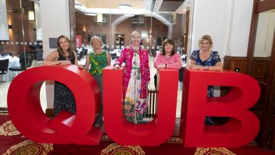 Large QUB letters with four ladies standing behind